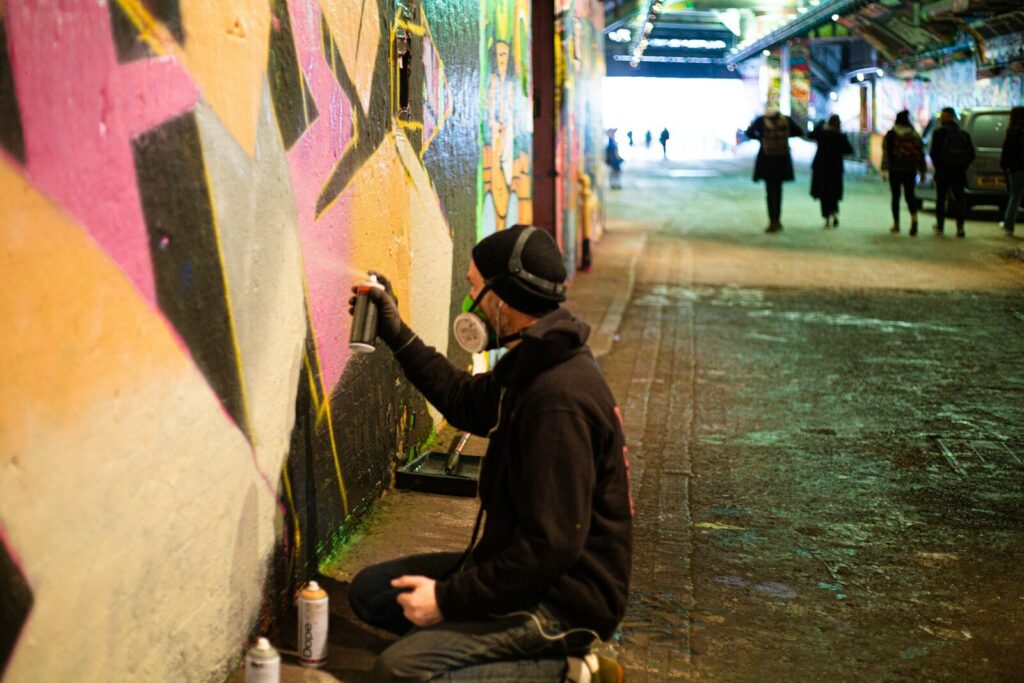 a man sitting on the ground painting a wall
